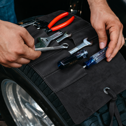 Black leather tool roll with tools on a tire